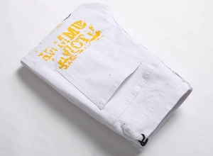Détail d'un pantalon en denim blanc avec lettrage artistique jaune et texture urbaine
