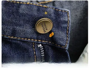 Makro-Detail von dunkelblauen Jeans mit Kupferknopf und gelben Kontrastnähten im Detail