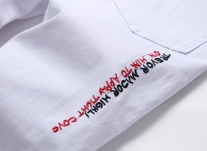 Macro shot of red and black letter embroidery on white distressed denim shorts fabric