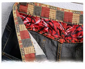 Macro view of blue denim shorts showing patterned inner waistband and copper rivets