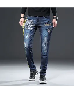 Détail de la broderie tête de tigre et des patchs usés sur un jean slim bleu pour homme