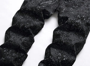 Detail of black technical pants featuring grey topographic map and contour line patterns
