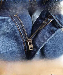 Gros plan sur la fermeture éclair YKK et les coutures contrastées du short denim