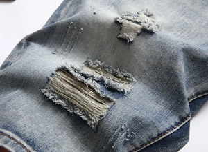 Close-up of distressed denim detailing with frayed rips on blue washed jean shorts