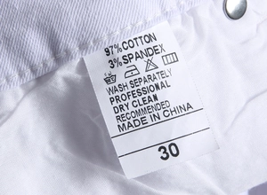 Detail of product label showing 97% cotton fabric composition on white denim shorts