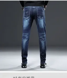 Détail de jean ajusté pour homme avec surpiqûres sur la poche arrière et texture denim