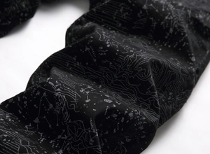 Detailed close-up of black denim fabric with silver graffiti art print and twill texture