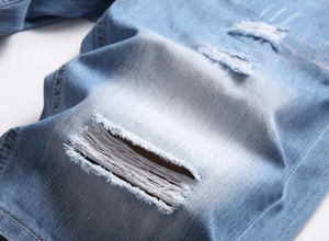 Gros plan détaillé du short en jean délavé bleu clair montrant la texture déchirée