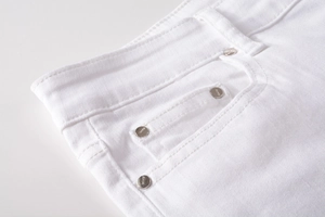 Macro shot of white denim waistline and pockets with silver metal rivet detail
