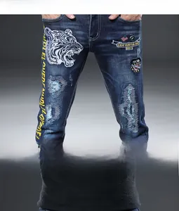Détails de broderie tigre blanc et écusson drapeau sur un jean stretch bleu pour hommes