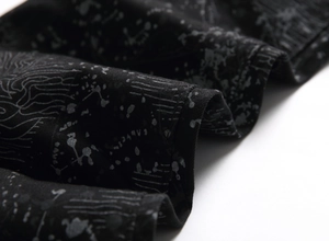 Close-up of black denim fabric with abstract grey graffiti print and woven texture