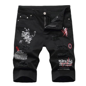 Detail of ripped black denim shorts with red graffiti print and clock badge patch