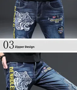 Détail de la broderie tête de tigre et de l'écusson drapeau sur jean bleu pour homme