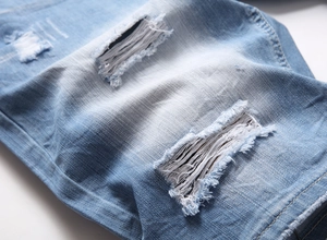 Vue macro du tissu denim avec trous déchirés et détails de moustaches de chat délavées