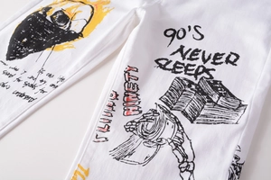 Detailed view of white street style denim pants with skull and yellow graffiti prints