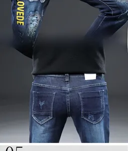 Vue détaillée du jean homme avec broderie, effet déchiré et finition denim bleu délavé