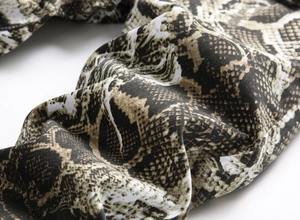 Macro view of textured snakeskin print fabric with detailed stitching on slim-fit denim jeans