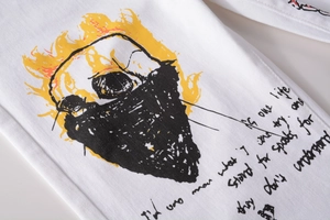 Detail of white street style trousers with flame skull graphic and graffiti lettering