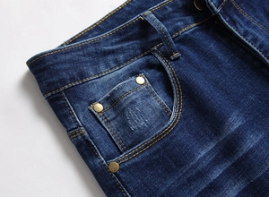 Detailaufnahme der dunklen Jeans-Taille mit gelben Kontrastnähten und Metallnieten-Design