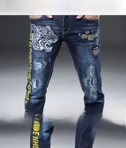 Détails de broderie tigre et écussons usés sur un jean slim en denim bleu extensible