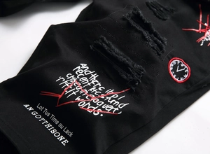 Detail of distressed black denim shorts with white graphic print and clock embroidery