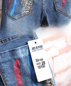 Détail des taches de peinture sur la poche de jean et étiquette affichant la taille 28