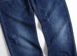 Detail einer dunkelblauen Slim Fit Jeans mit Wascheffekt und Distressed-Textur am Bein
