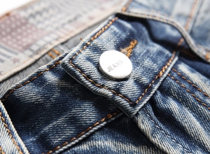 Close-up of distressed denim shorts showing metal button and orange contrast stitching