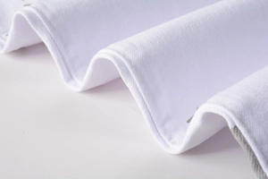 Detail of white camouflage jeans fabric showing twill texture and reinforced stitching