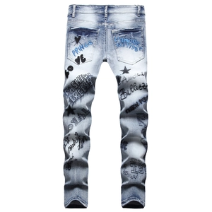 Detail view of light blue jeans featuring black and blue graffiti embroidery on back pockets