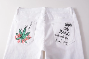 Detail of white denim pants back pockets with green leaf print and graffiti text design