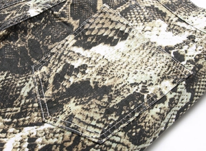 Close-up of snake skin print texture on denim fabric with reinforced back pocket stitching
