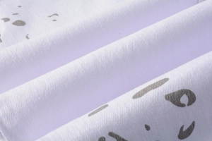 Close-up of white textile fabric featuring grey abstract camo print and fine woven texture
