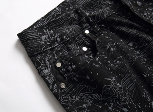 Detailed close-up of jeans with artistic silver splatter print and branded metal rivets