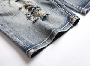 Detail of light blue denim shorts featuring heavy distressed rips and vintage wash finish