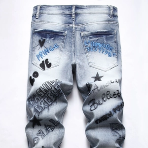 Detailed back view of light blue washed jeans with street-style embroidery and graphics