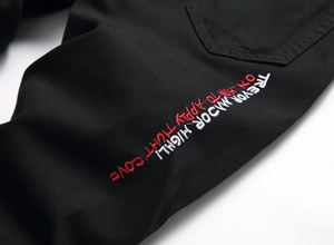 Detailed view of black denim fabric featuring red and white embroidery and twill texture