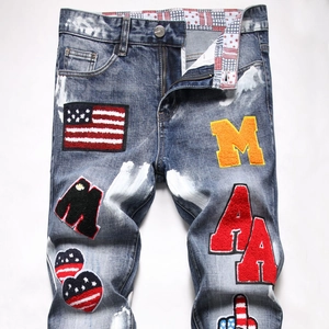Detail of washed denim jeans with American style chenille patches and white paint splatters