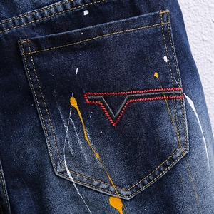 Detail der dunkelblauen Denim-Shorts mit bunten Farbspritzern und V-Logo-Stickerei