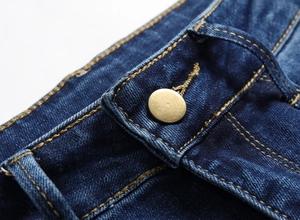 Detaillierte Nahaufnahme der dunkelblauen Jeans-Taille mit Metallknopf und gelber Kontrastnaht