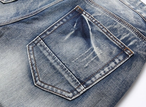 Macro shot of men's distressed denim shorts featuring pocket stitching and wash details