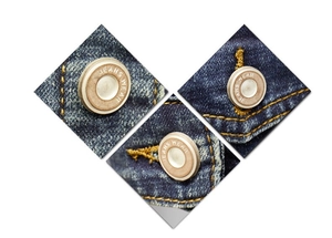 Detail of vintage metal jeans buttons on dark blue twill denim jacket fabric