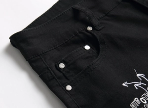 Detailed close-up of black denim waist featuring metal rivets and embroidery accents