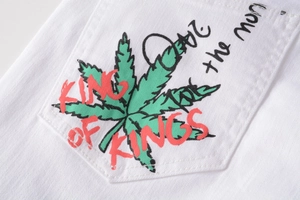 Detailed view of the white denim pocket featuring a green leaf and King of Kings text