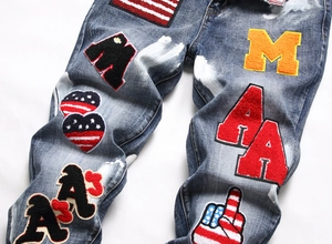 Detail of blue wash denim jeans with American style towel embroidery patches and moustaches