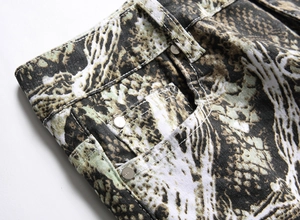 Close-up of hip hop style snakeskin print jeans featuring waist rivets and twill fabric texture