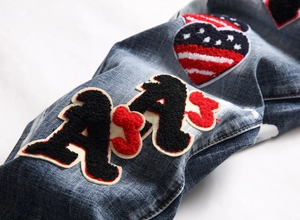 Macro shot of Chenille letter AJ and heart American flag patch on washed denim jeans