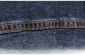 Macro shot of double yellow stitching and seam detail on premium navy denim jacket fabric