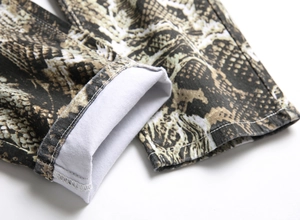 Detailed macro view of snakeskin print denim fabric with clean white stitching and hem