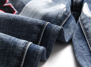 Macro view of blue washed denim fabric with detailed towel embroidery badge and twill texture